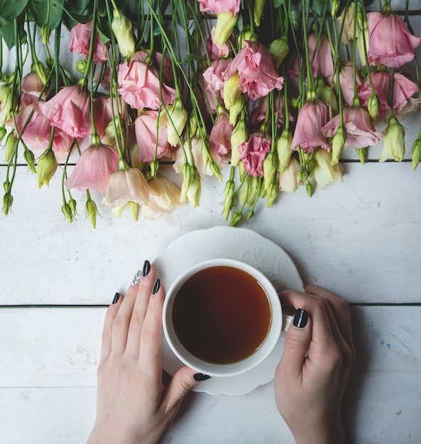 Una taza de té negro y flores amarillas y rosadas