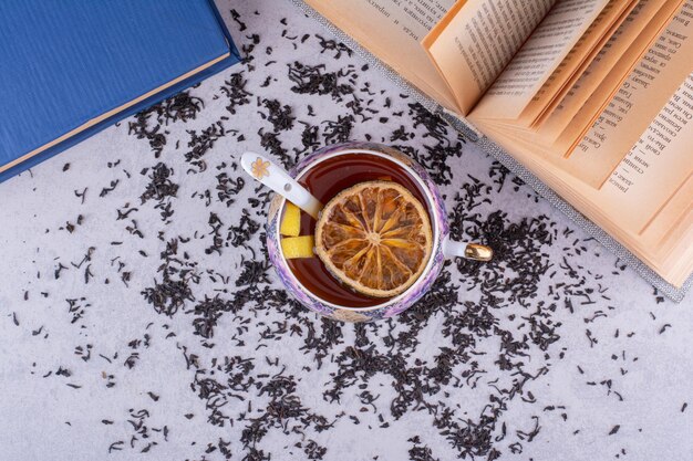 Taza de té negro con rodajas de frutas y libros. Foto de alta calidad