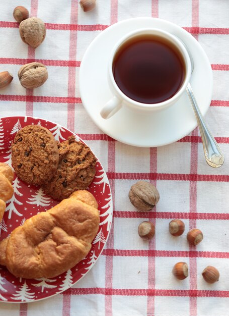 Una taza de té con nueces y pasteles sobre el mantel facturado. Vista superior.