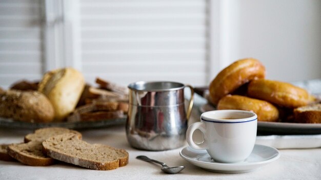 Taza de té con pan y donas en la mesa