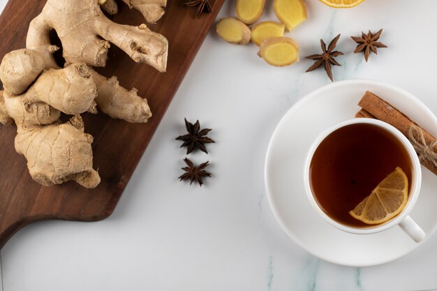 Una taza de té y plantas de jengibre en una tabla de madera