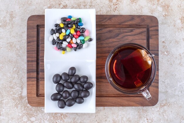 Taza de té y plato de chocolates sobre plancha de madera