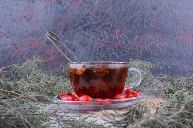 Taza de té con rosa mosqueta fresca sobre mesa de mármol. Foto de alta calidad