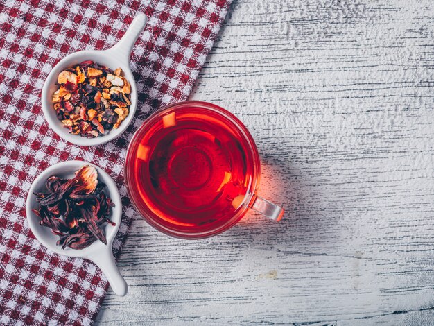 Taza de té con té de hierbas vista superior sobre un paño de picnic y fondo de madera gris