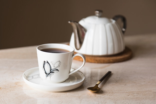 Taza de té con tetera y elementos de desayuno