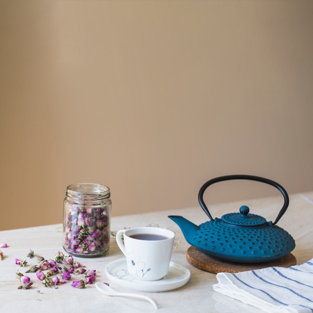 Taza de té con tetera y elementos de desayuno