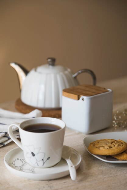 Taza de té con tetera y elementos de desayuno