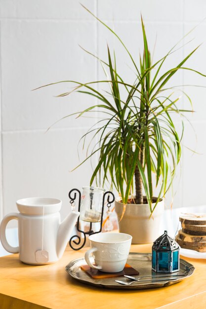 Taza de té con tetera y elementos de desayuno