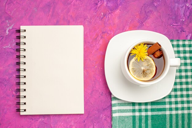 Taza de té de vista superior en toalla verde con cuaderno en rosa