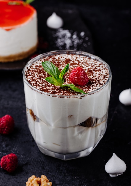 Taza de tiramisú con cacao en polvo y frambuesa con menta.