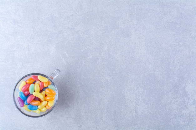 Una taza de vidrio llena de coloridos caramelos de frijoles.