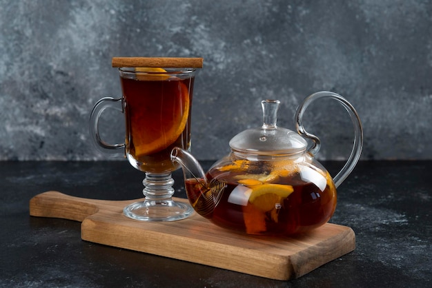 Una taza de vidrio con té y canela en rama.