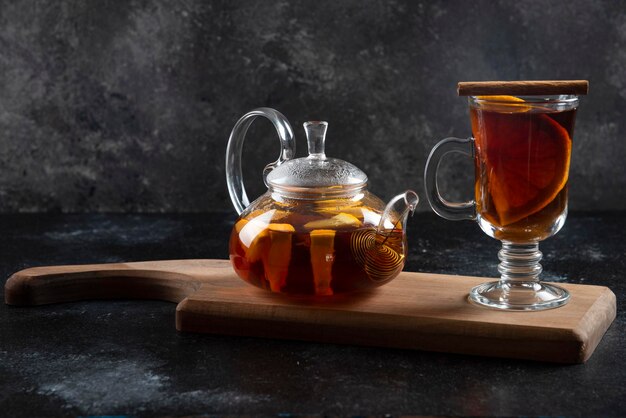 Una taza de vidrio con té y canela en rama.