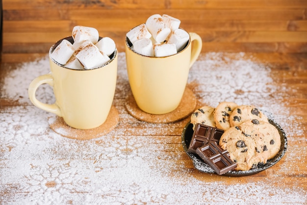 Tazas de cacao con dulces en mesa