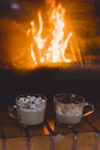 Foto gratuita tazas de cacao con malvaviscos junto a la chimenea.