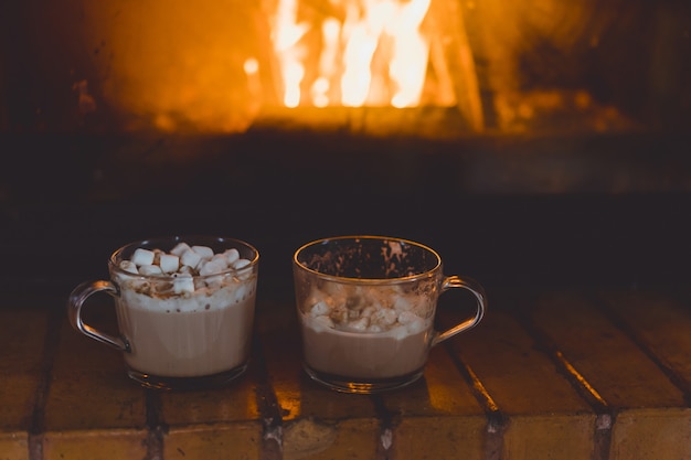 Tazas de cacao con malvaviscos junto a la chimenea.