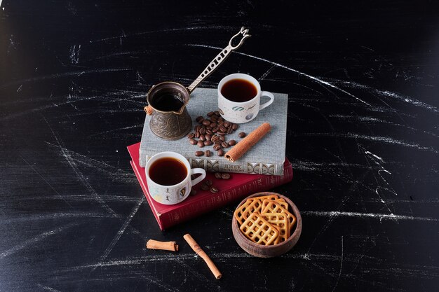 Tazas de café con frijoles alrededor.