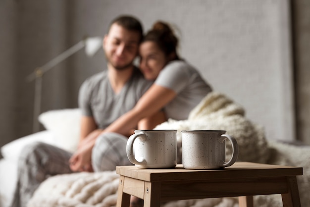 Tazas de café sobre la mesa con la joven pareja detrás