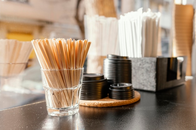 Tazas de café con tapas y palos de madera en el mostrador de la cafetería.