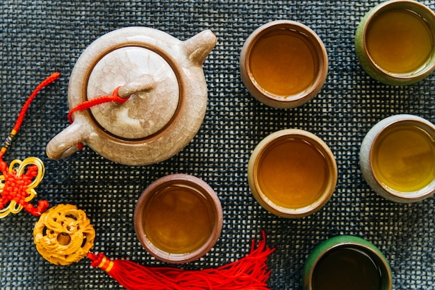 Tazas de té de cerámica y tetera con borla en mantel individual