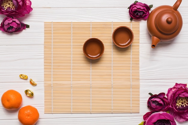 Tazas de té cerca de flores y mandarinas