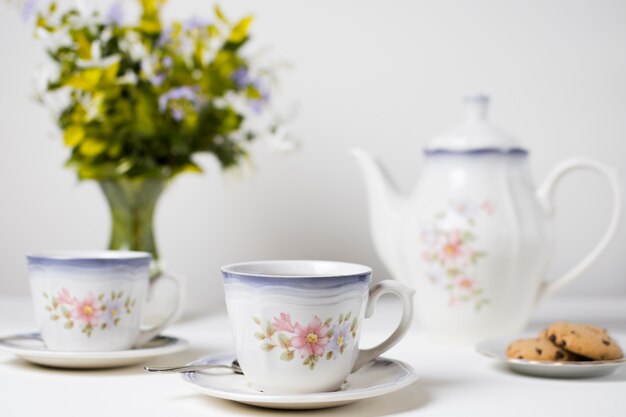 Tazas de té y galletas de cerámica en mesa blanca