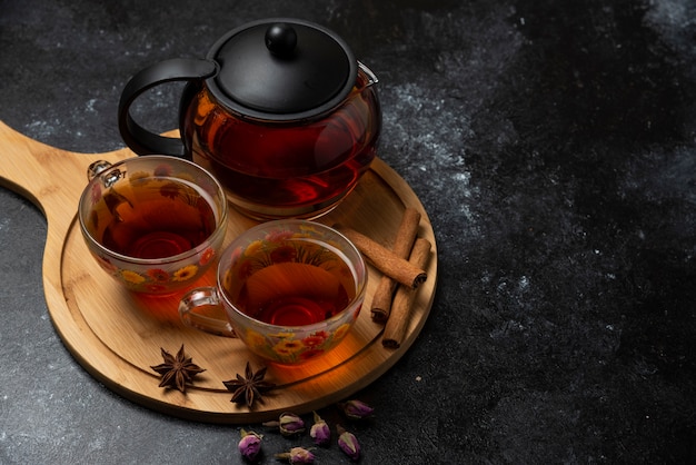 Tazas de té de hierbas con especias sobre la plancha de madera.