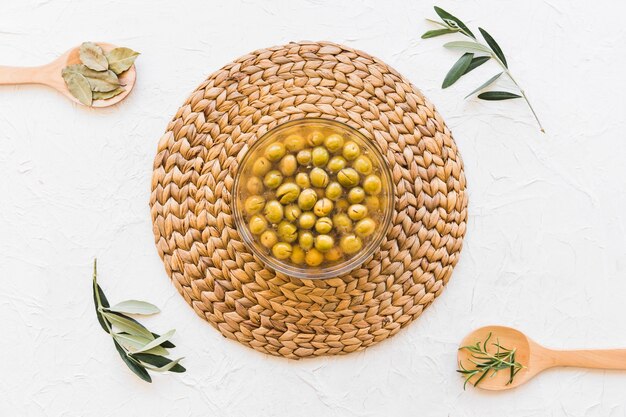 Tazón con aceitunas y aceite y hierbas sobre fondo blanco