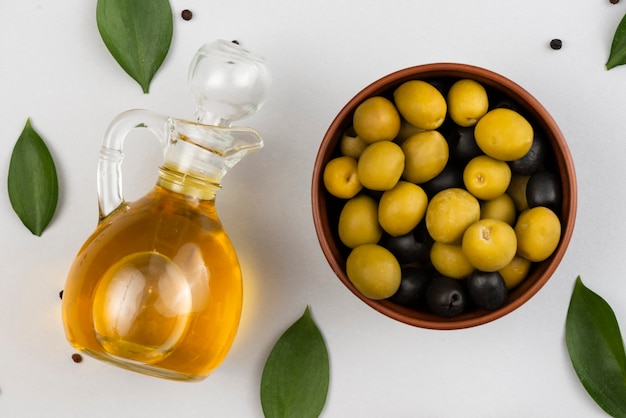 Foto gratuita tazón con aceitunas y botella de aceite de aceitunas