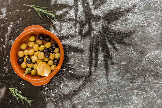 Foto gratuita tazón con aceitunas cerca de hojas verdes