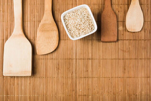 Tazón de arroz integral crudo con espátulas de madera sobre el mantel