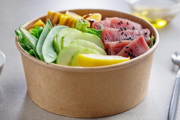 Tazón de atún crudo saludable con verduras servido en tazón de papel. De cerca