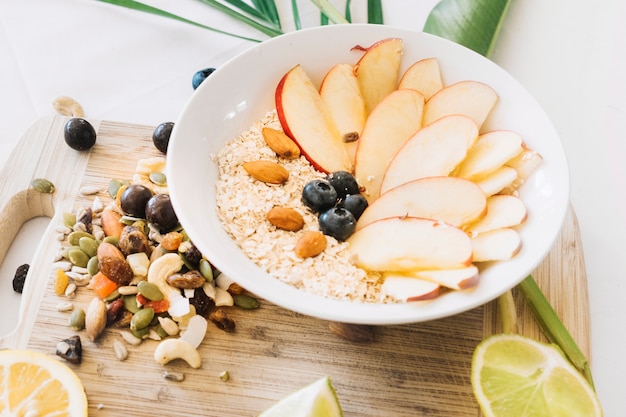 Tazón de avena con una rebanada de manzana y frutos secos en una tabla de cortar