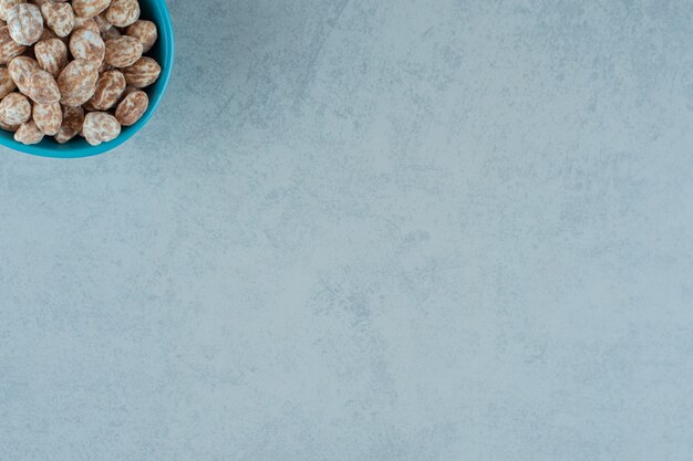 Un tazón azul lleno de dulce delicioso pan de jengibre sobre superficie blanca