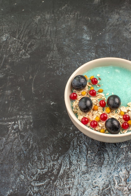 Foto gratuita tazón de bayas azul de las apetitosas bayas en la mesa gris