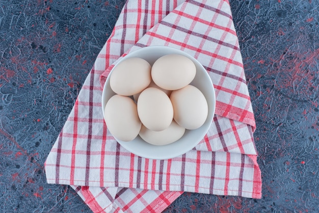 Un tazón blanco con huevos de gallina crudos frescos.