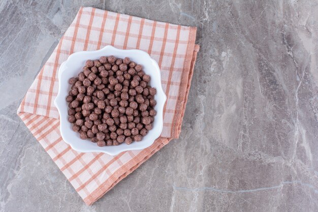 Un tazón blanco lleno de deliciosas bolas de maíz con chocolate sobre un mantel.