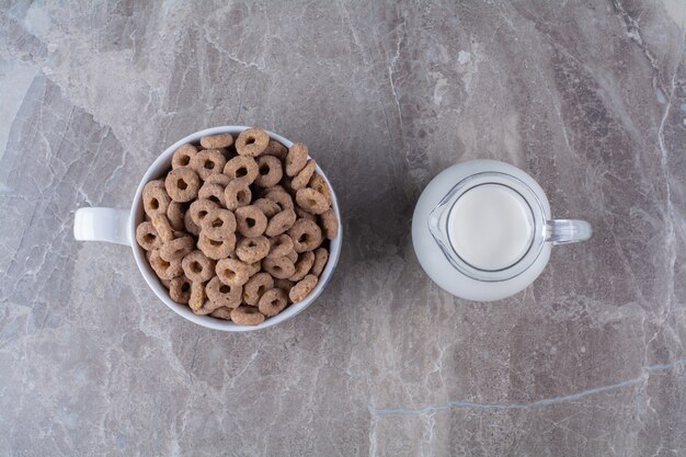 Un tazón de cereales de chocolate saludables suena con un tarro de cristal de leche.