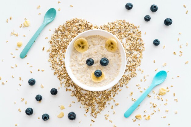 Tazón con copos de avena y frutas con forma de corazón en el escritorio