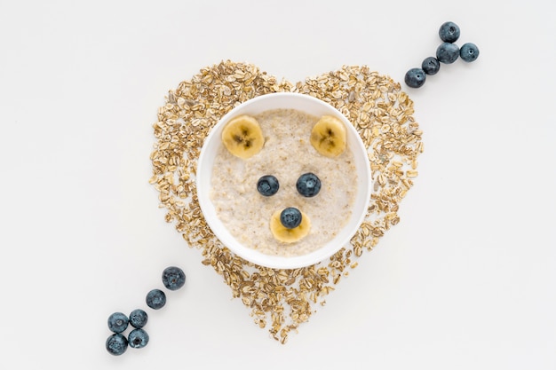 Tazón con copos de avena y frutas con forma de corazón en la mesa