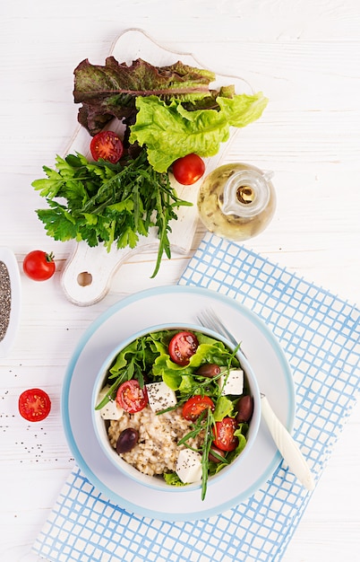 Tazón de desayuno con avena, tomate, queso, lechuga y aceitunas