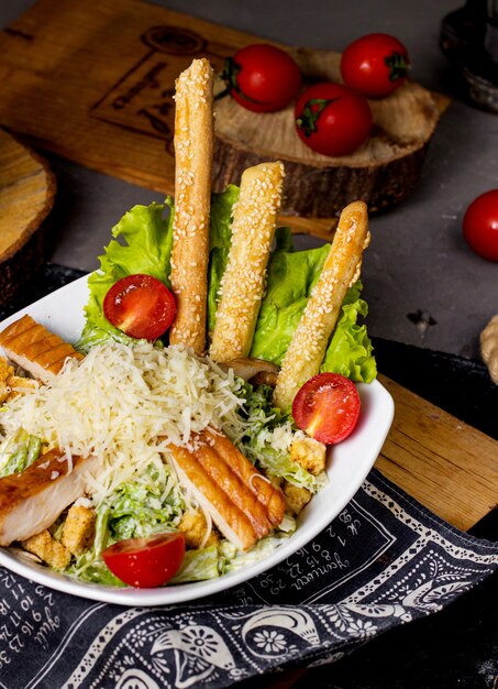 Un tazón de ensalada César adornado con palitos de pan