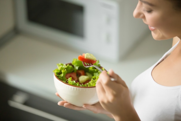 Tazón de ensalada de ensalada verde fresco en las manos femeninas