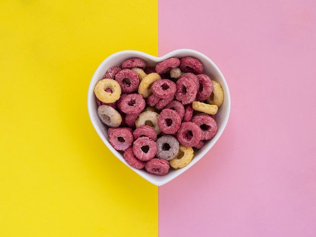 Tazón en forma de corazón lleno de aros de frutas rosas y amarillas