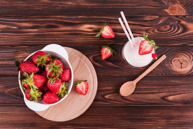 Tazón de fresas y batido en la mesa