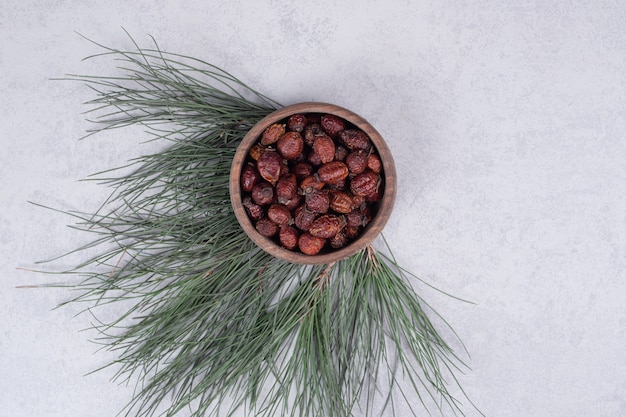 Tazón de fuente de arándanos secos y rama de pino sobre mesa de mármol. Foto de alta calidad