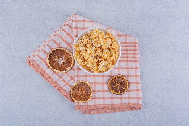 Tazón de fuente blanco de caramelos duros con nueces y rodajas de limón en la mesa de piedra.