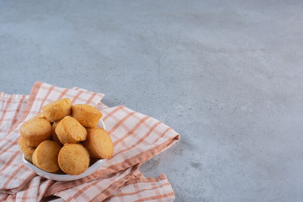 Tazón de fuente blanco de mini tortas dulces en la mesa de piedra.