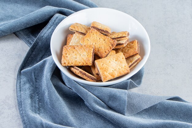 Tazón de fuente blanco de sabrosas galletas crujientes en piedra.