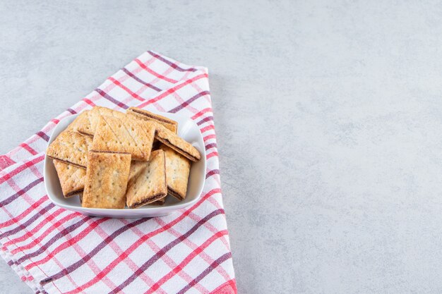 Tazón de fuente blanco de sabrosas galletas crujientes en piedra.